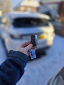Range Rover Evoque semi smart key being held up in front of white car