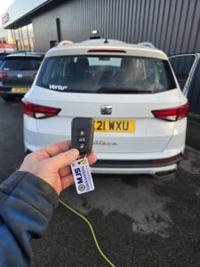 New Seat spare key cut and programmed outside car dealership showing new black key and MJS key tag in white
