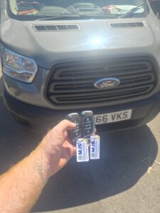 New key and spare key held up in front of van during programming after all keys lost to a 2016 transit van