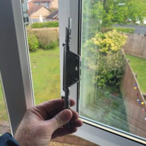 Window lock gearbox being held up in front of upvc window in the open position